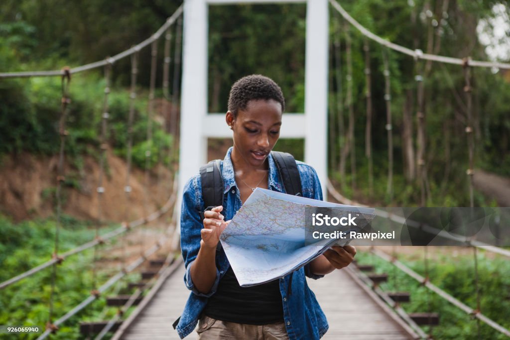 Mulher afro-americana a olhar para um mapa viajar e explorar o conceito - Foto de stock de Mapa royalty-free