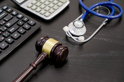 Wooden judge gavel, calculator and stethoscope on table