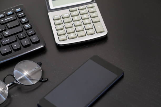 istock Office black Desk table with computer, calculator, smartphone, glasses, pan, supplies. Top view with copy space. Business jobs and business objects 926069894