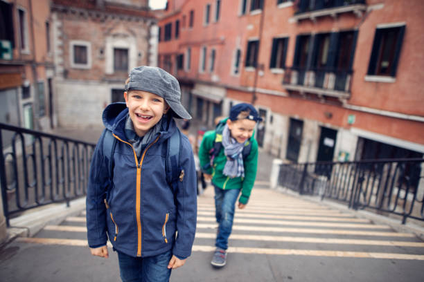 Happy boys enjoying sightseeing Venice. The boys aged 7 are walking over San Pantalon Bridge (Ponte di San Pantalon) amd laughing at the camera.