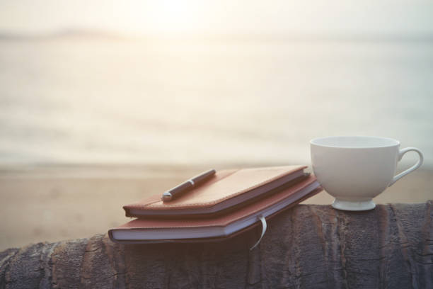 istock Notebooks,books, pen and a cup of coffee on the beach. 926070438