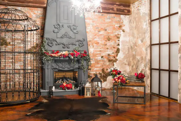 Photo of Interior with fireplace, candles, skin of cows, brick wall, large window and a metal cell of a loft, living room, coffee table in modern design