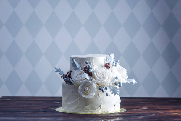 istock Delicate white bunk wedding cake decorated with an original design using mastic roses. Concept of festive desserts 926077074