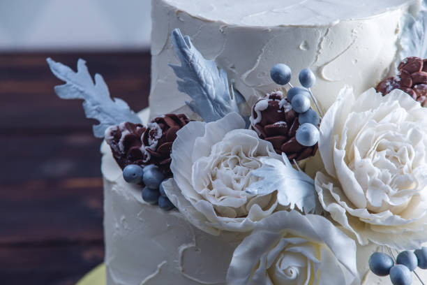 istock Delicate white bunk wedding cake decorated with an original design using mastic roses. Concept of festive desserts 926077076