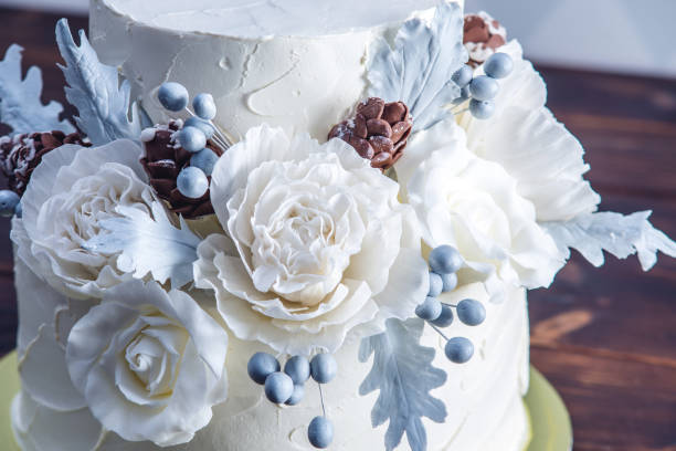 istock Delicate white bunk wedding cake decorated with an original design using mastic roses. Concept of festive desserts 926077084