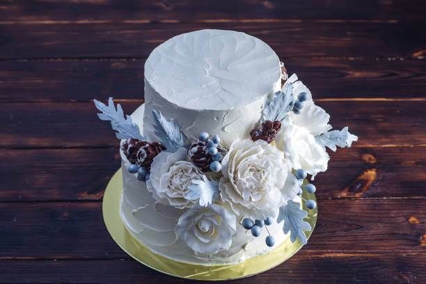 istock Delicate white bunk wedding cake decorated with an original design using mastic roses. Concept of festive desserts 926077086
