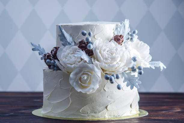Delicate white bunk wedding cake decorated with an original design using mastic roses. Concept of festive desserts stock photo