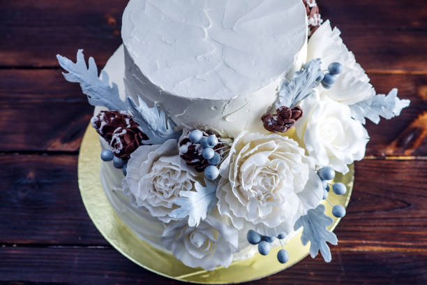 istock Delicate white bunk wedding cake decorated with an original design using mastic roses. Concept of festive desserts 926077102