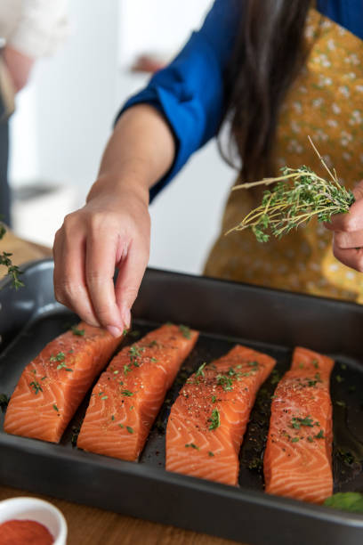 istock Woman adding spices and herb to raw salmon 926077922