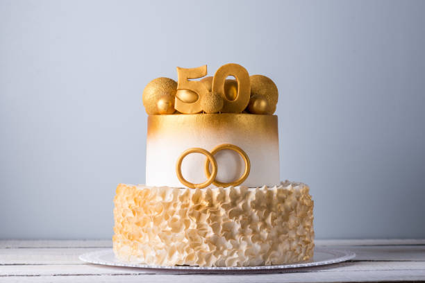 Beautiful cake for the 50th anniversary of the wedding decorated with gold balls and rings. Concept of festive desserts stock photo