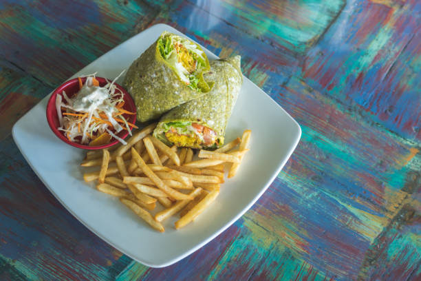 Plate served with a falafel wrap, vegetable salad, and french fries