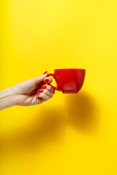 istock Hand holding the red mug on a bright yellow background 926084606