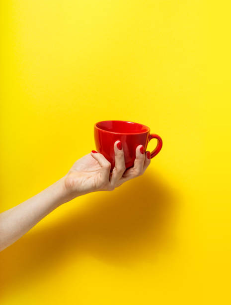 istock Hand holding the red mug on a bright yellow background 926084608