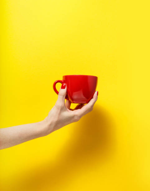 istock Hand holding the red mug on a bright yellow background 926084618