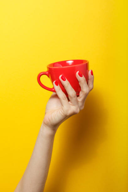 istock Hand holding the red mug on a bright yellow background 926084664
