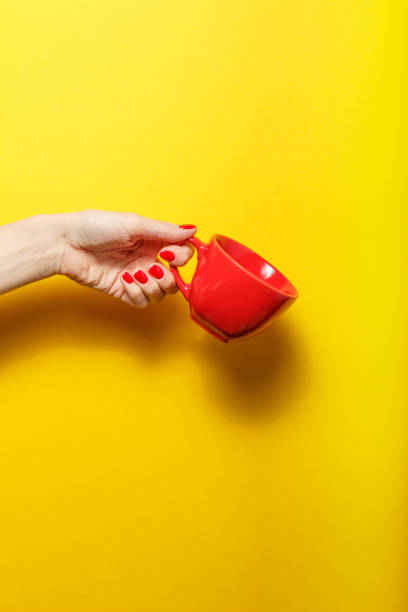 istock Hand holding the red mug on a bright yellow background 926084678
