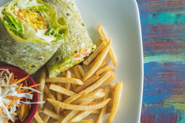 Plate served with a falafel wrap, vegetable salad, and french fries