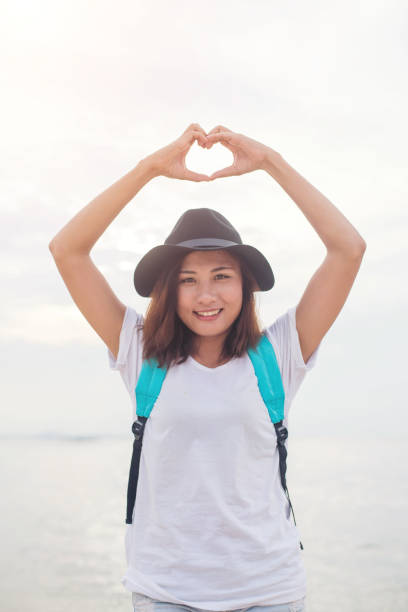 istock Young woman doing heart shaped.Summertime horizontal outdoors seaside beach background. 926089228