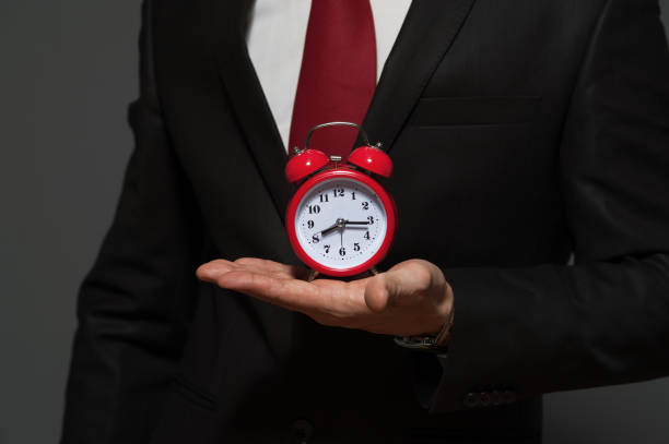 istock Handsome businessman in formal suit holding clock 926093488