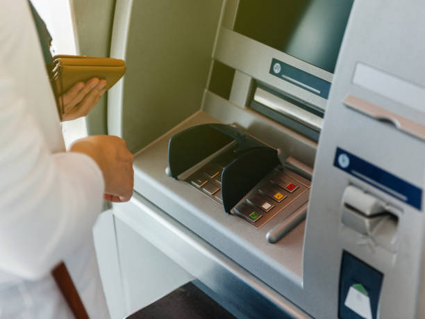 istock Side view of woman using ATM holding wallet an pressing the PIN 926102002
