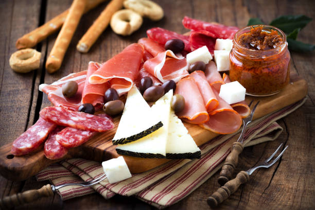 Cured meat and cheese platter Cured meat and cheese platter of traditional Spanish tapas - chorizo, salsichon, jamon serrano, lomo and slices of goat cheese - served on wooden board with olives and bread sticks italian cheese stock pictures, royalty-free photos & images