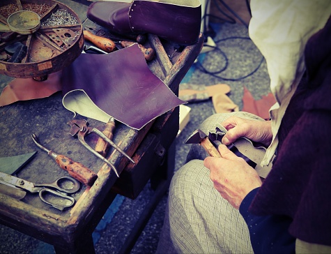 cobbler repairs the shoes with a piece of leather with vintage effect