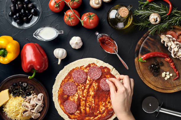 istock Hands of baker adding ingredients into pizza during pizza preparation at kitchen 926116592