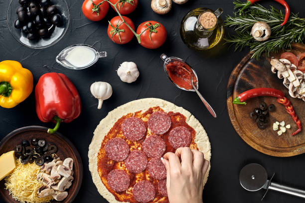 istock Hands of baker adding ingredients into pizza during pizza preparation at kitchen 926116894