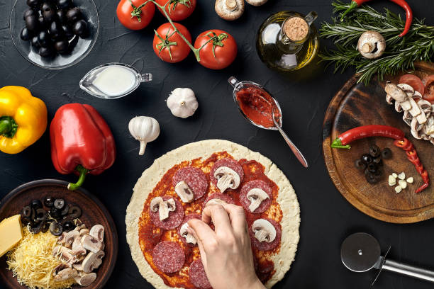 istock Hands of baker adding ingredients into pizza during pizza preparation at kitchen 926117172
