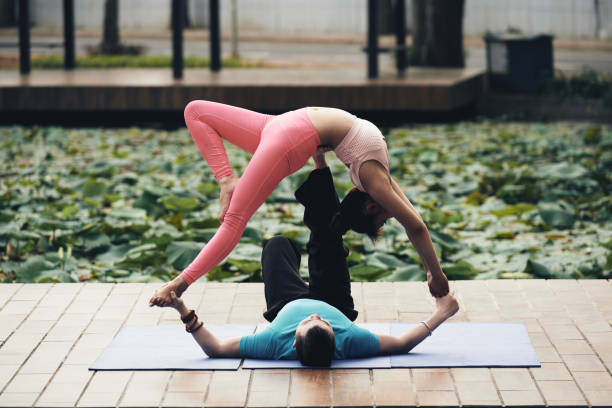 Couple yoga Young Asian couple enjoying practicing acroyoga outdoors acroyoga stock pictures, royalty-free photos & images