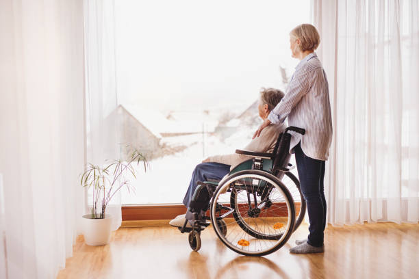 пожилые женщины с инвалидной коляской дома. - senior adult winter senior women daughter стоковые фото и изображения