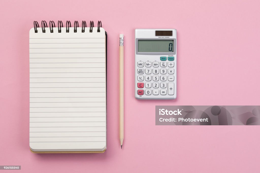 Workspace - Concept Spiral notebook, pencil and calculator on pink background Calculator Stock Photo