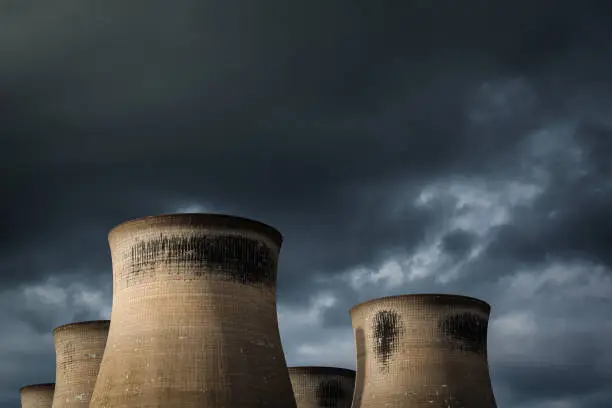 Landscape image of a power stations cooling towers with a moody overcast sky