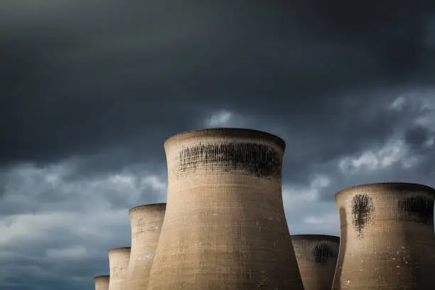 Landscape image of a power stations cooling towers with a moody overcast sky