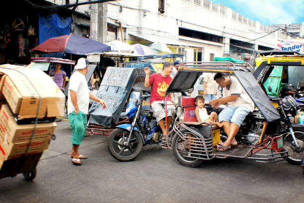 Road traffic in Manila, Philippines, with the typical tuk tuks Manila, Philippines - february 3rd, 2013: road traffic in the capital city with the typical motor-bike tuk tuks philippines tricycle stock pictures, royalty-free photos & images