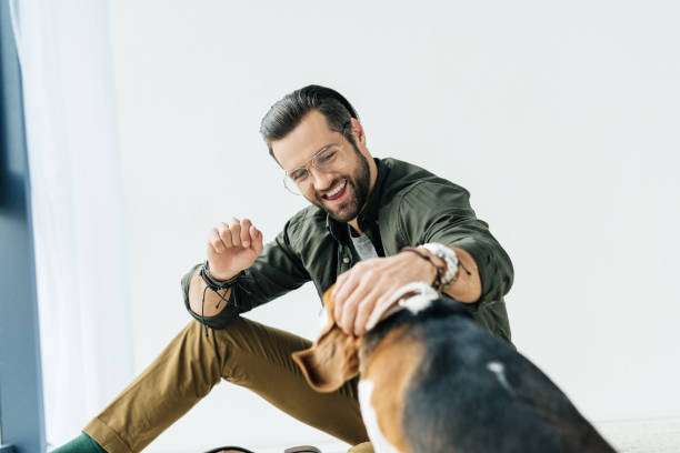 istock happy man sitting on floor and playing with dog 926158978