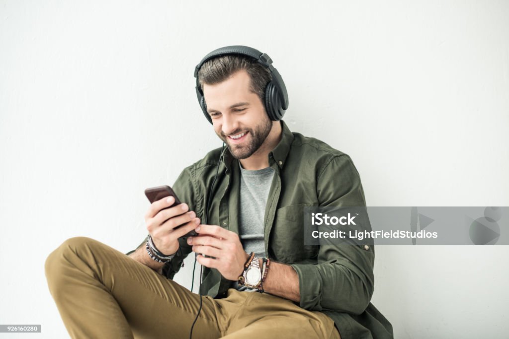 beau sourire homme écoute la musique avec smartphone isolé sur blanc - Photo de Casque audio libre de droits