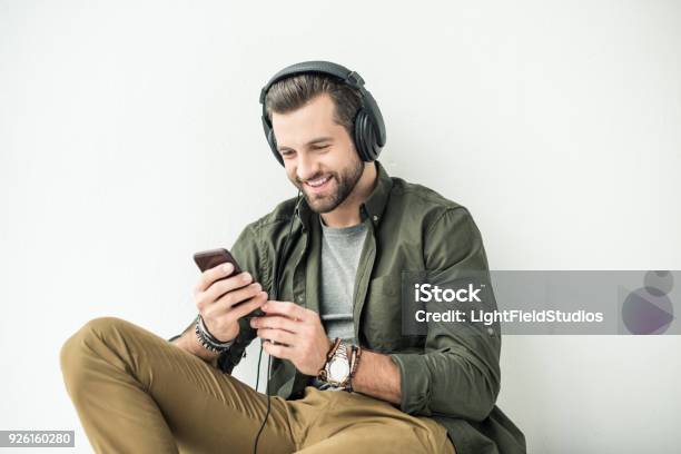 Photo libre de droit de Beau Sourire Homme Écoute La Musique Avec Smartphone Isolé Sur Blanc banque d'images et plus d'images libres de droit de Casque audio