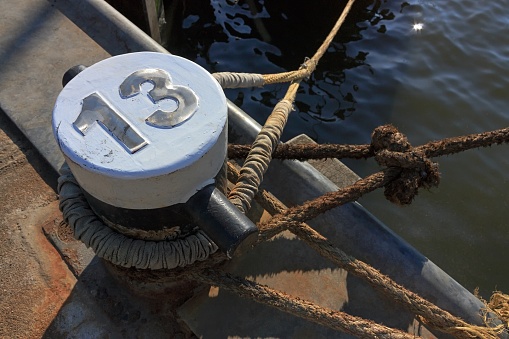 Mooring lines and bollard in harbor with number 13