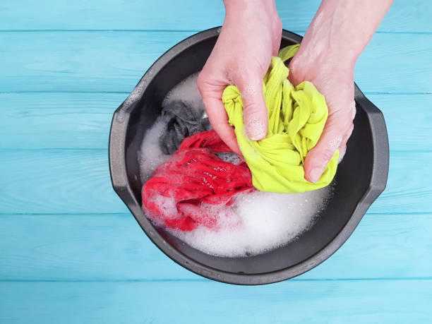 istock hands washing clothes in basin wooden background 926163756