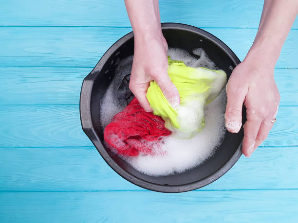 istock hands washing clothes in basin wooden background 926164324