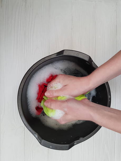 istock hands washing clothes in basin wooden background 926167024