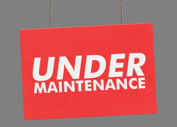 Photo of Under maintenance sign hanging from ropes. Clipping path included so you can put your own background.