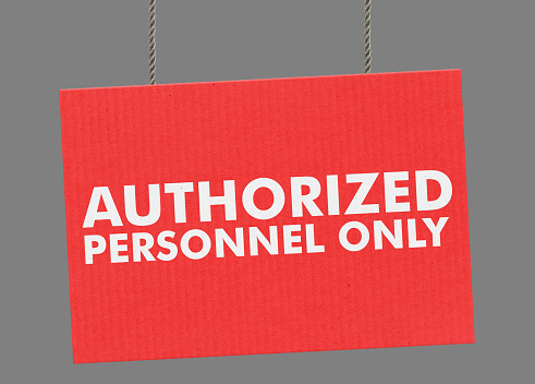 Cardboard Authorized personnel only sign hanging from ropes. Clipping path included so you can put your own background