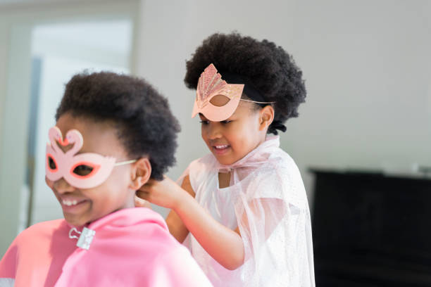 ragazza sorridente che assiste la sorella nell'indossare la maschera - focus on foreground joy happiness pink foto e immagini stock