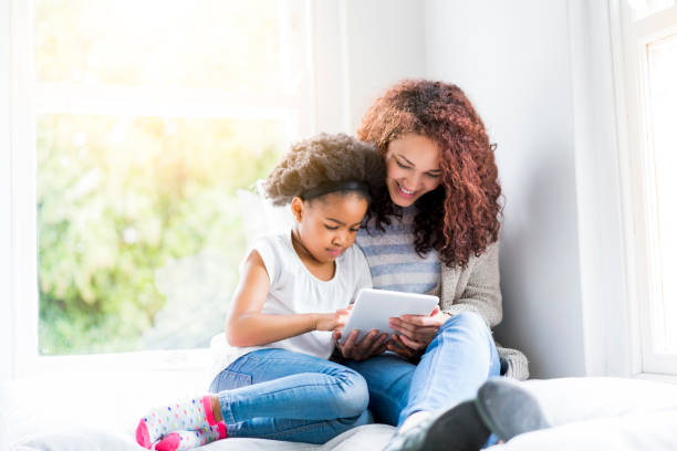 istock Mother and daughter with tablet PC on window seat 926171684