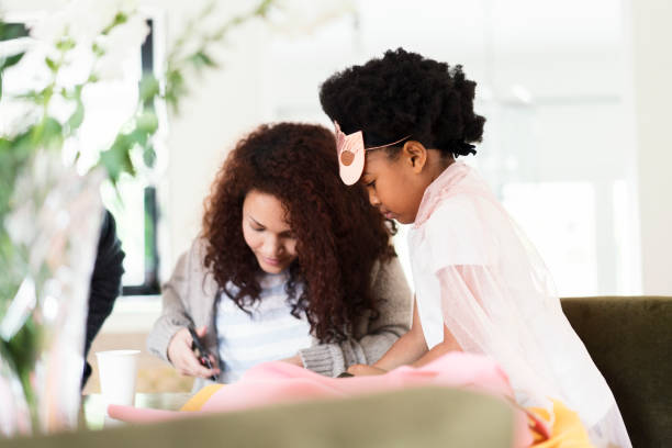 istock Daughter looking at mother cutting cape at home 926171722