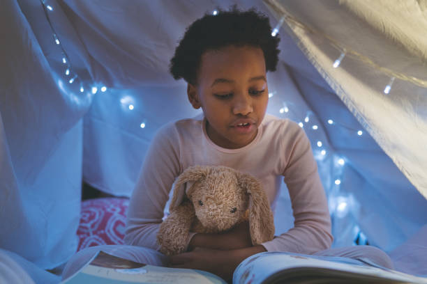 istock Girl reading book in illuminated tent 926172034