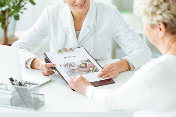 Close-up of diet plan Close-up photo of dietician showing diet plan to her patient nurse smock stock pictures, royalty-free photos & images