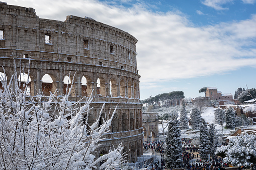 Rome, Italy - February 26, 2018: An exceptional weather event causes a cold and cold air across Europe, including Italy. Snow comes in the capital, covering streets and monuments of a white white coat. In the picture, Piazza del Colosseo comes alive with hundreds of people who went out to celebrate the event.